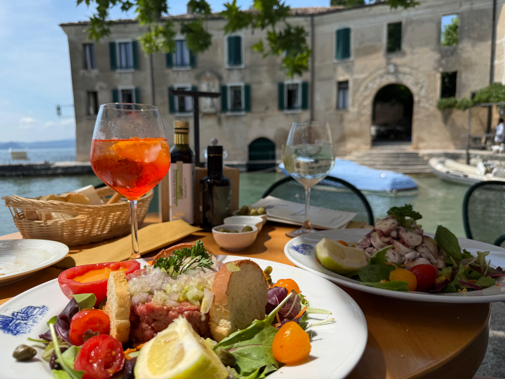 Steak tartare and octopus salad with an Aperol Spritz on the terrace of Locanda San Vigilio, overlooking the lake and the historic villa.