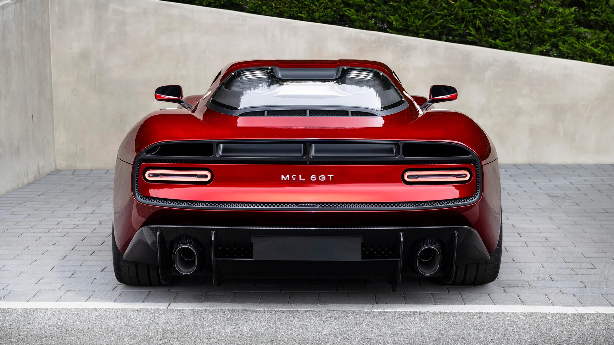 Rear view of the red McLaren McL 6GT showing its wide tail, twin round lamps and McL 6GT lettering